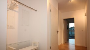 A hallway with a bench, a coat rack, and a door leading to another room. - Wohnen am Yachthafen W45 (Cuxhaven)