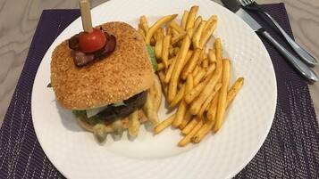 A plate with a burger and fries on a white plate, placed on a textured mat.