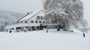 A snow-covered building with a large tree in front. - Hotel Restaurant Le Cleebourg (Rott)
