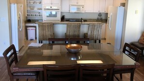A dining area with a glass table, four wooden chairs, and a central bowl. - THANK YOU 2025 RENTERS for 100%. 2026 only 3 weeks left DIRECT OCEAN FRONT 5BR  (Myrtle Beach)