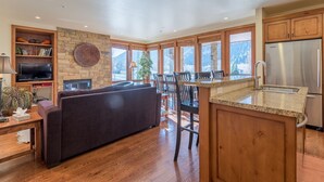 A modern kitchen with a stone wall, wooden cabinets, and a large island with a sink.