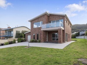 A two-story house with a brick exterior, a front garage, and a well-maintained lawn.