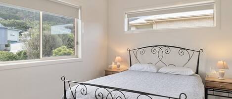 A bedroom with a bed, two bedside tables, a window, and a ceiling fan.