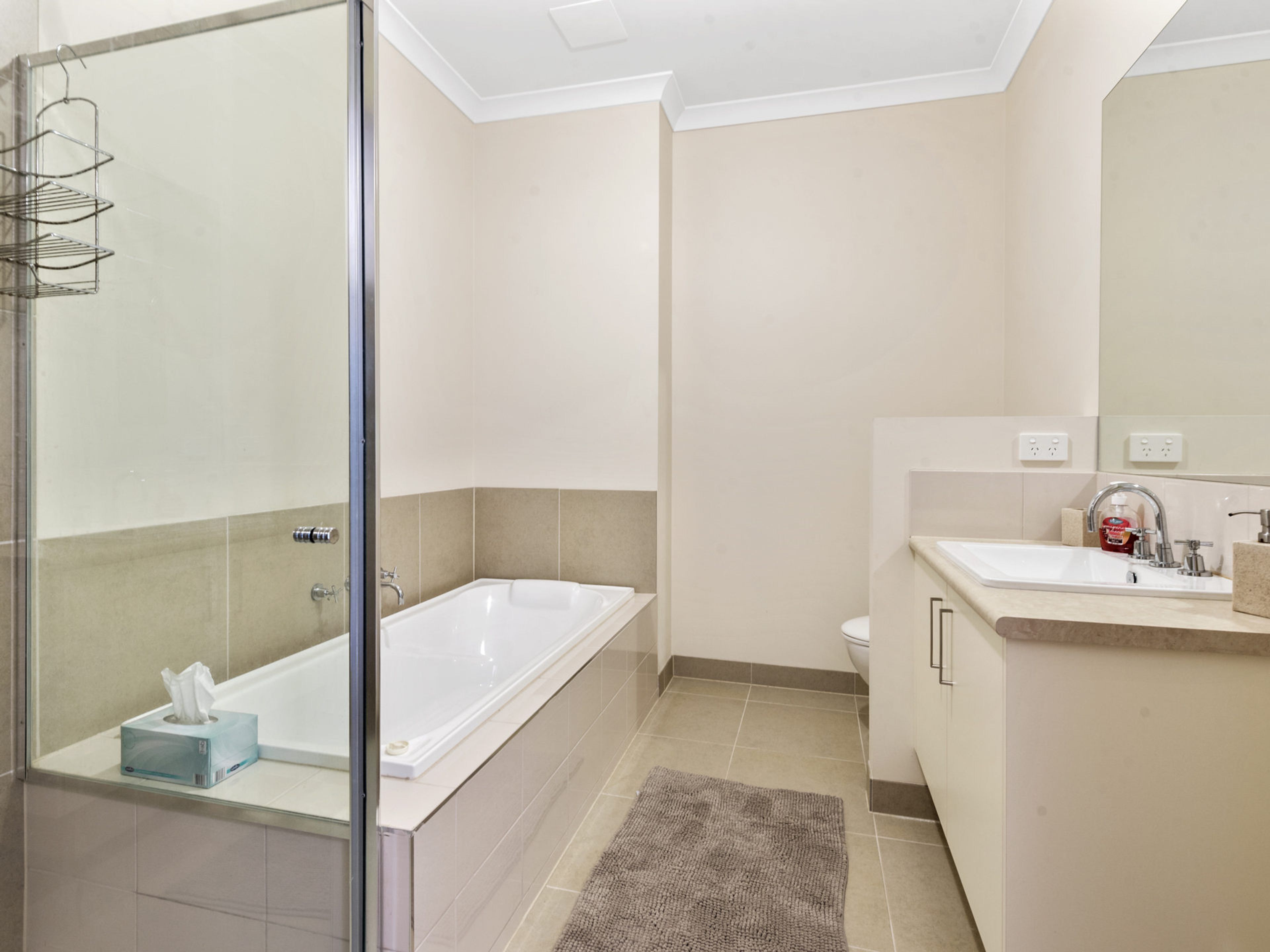 A modern bathroom with a glass shower enclosure, a standalone bathtub, a toilet, and a sink with a mirror.
