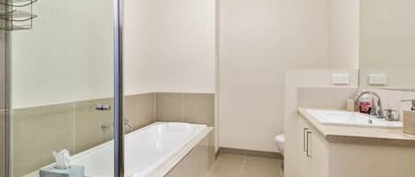 Un baño moderno con cabina de ducha de vidrio, bañera independiente, inodoro y lavabo con espejo.