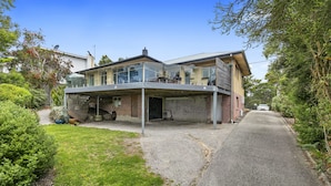 A modern two-story house with a covered patio and a driveway leading to the entrance.