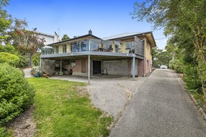 A modern two-story house with a covered patio and a driveway leading to the entrance.