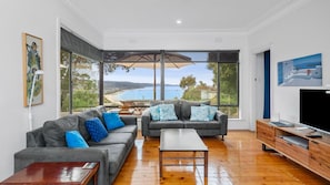 Enjoy a panoramic view of the coast from this living room, featuring a large window and comfortable seating area.