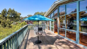 Enjoy expansive views of the surrounding landscape from the outdoor deck, featuring a table and chairs under a shaded area.