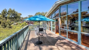 Enjoy expansive views of the surrounding landscape from the outdoor deck, featuring a table and chairs under a shaded area.