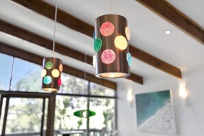 A modern interior with exposed wooden beams and pendant lights with colorful, textured glass shades.