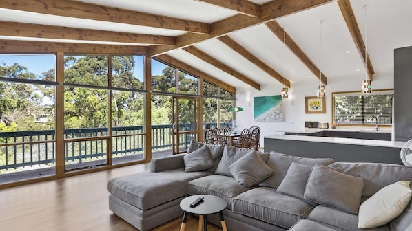 Relax in this spacious living area with a large sofa and dining table, surrounded by natural views.