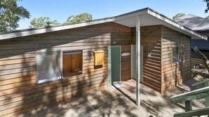 Situated on a wooden deck, this cabin features a large window, a door, and a small window.