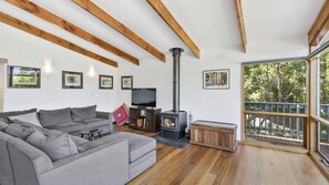 Relax in this cozy living space with a large sofa, flat-screen TV, and wood-burning stove.