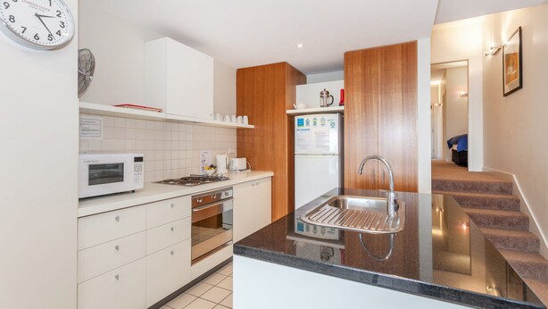 Eine moderne Küche mit weißen Schränken, einer Mikrowelle, einem Toaster und einem Spülbecken.