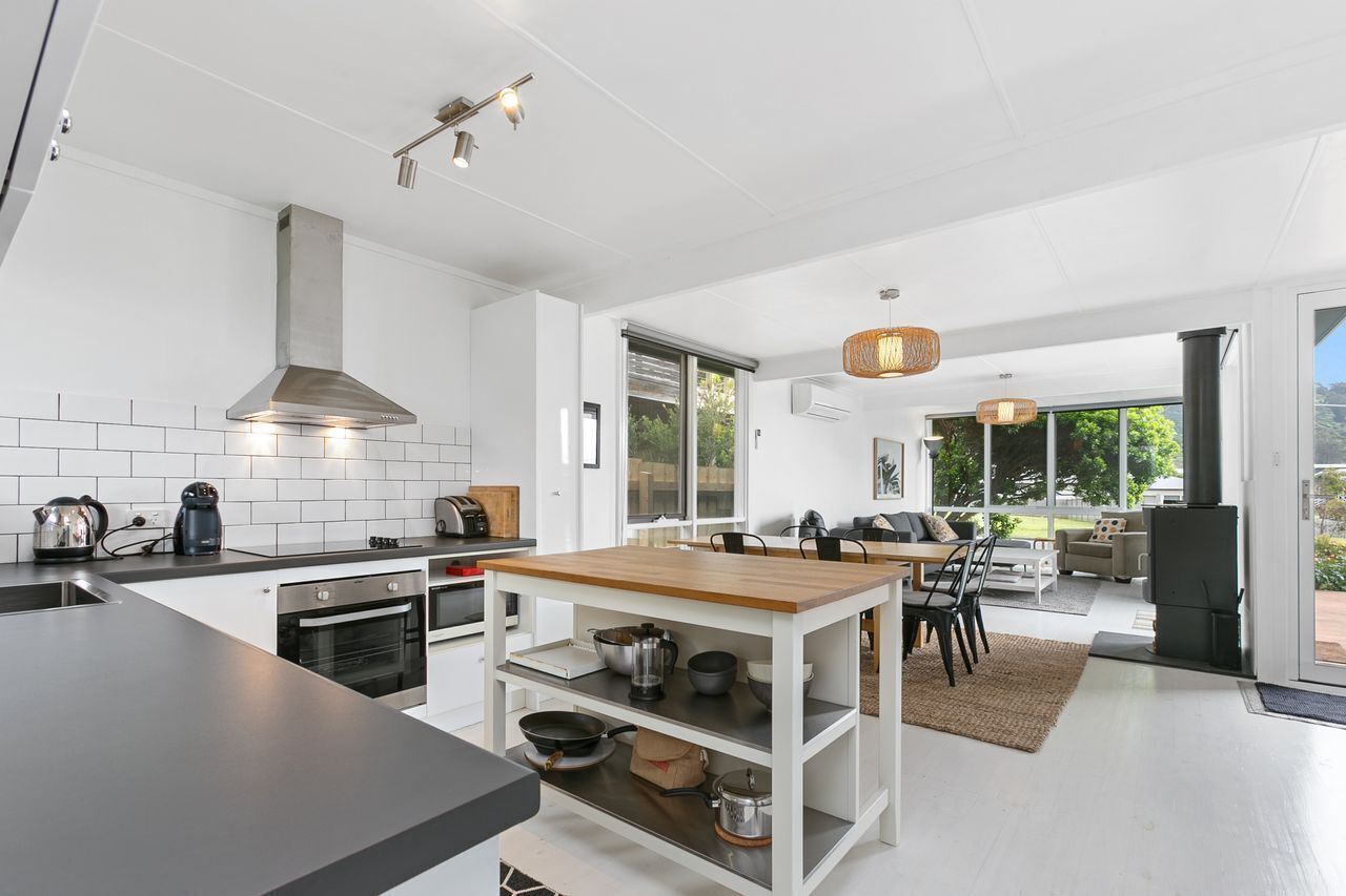 Een moderne keuken met een centraal eiland, een ingebouwde oven en een groot raam.