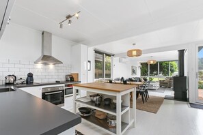 Eine moderne Küche mit Kochinsel, integriertem Backofen und großem Fenster.