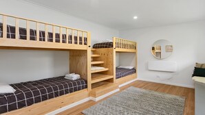 Een slaapkamer met een stapelbed, een spiegel, een tafeltje en een vloerkleed.