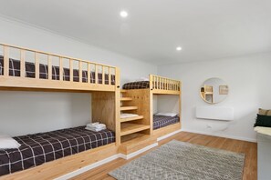 Ein Schlafraum mit Etagenbett, Spiegel, kleinem Tisch und Teppich.