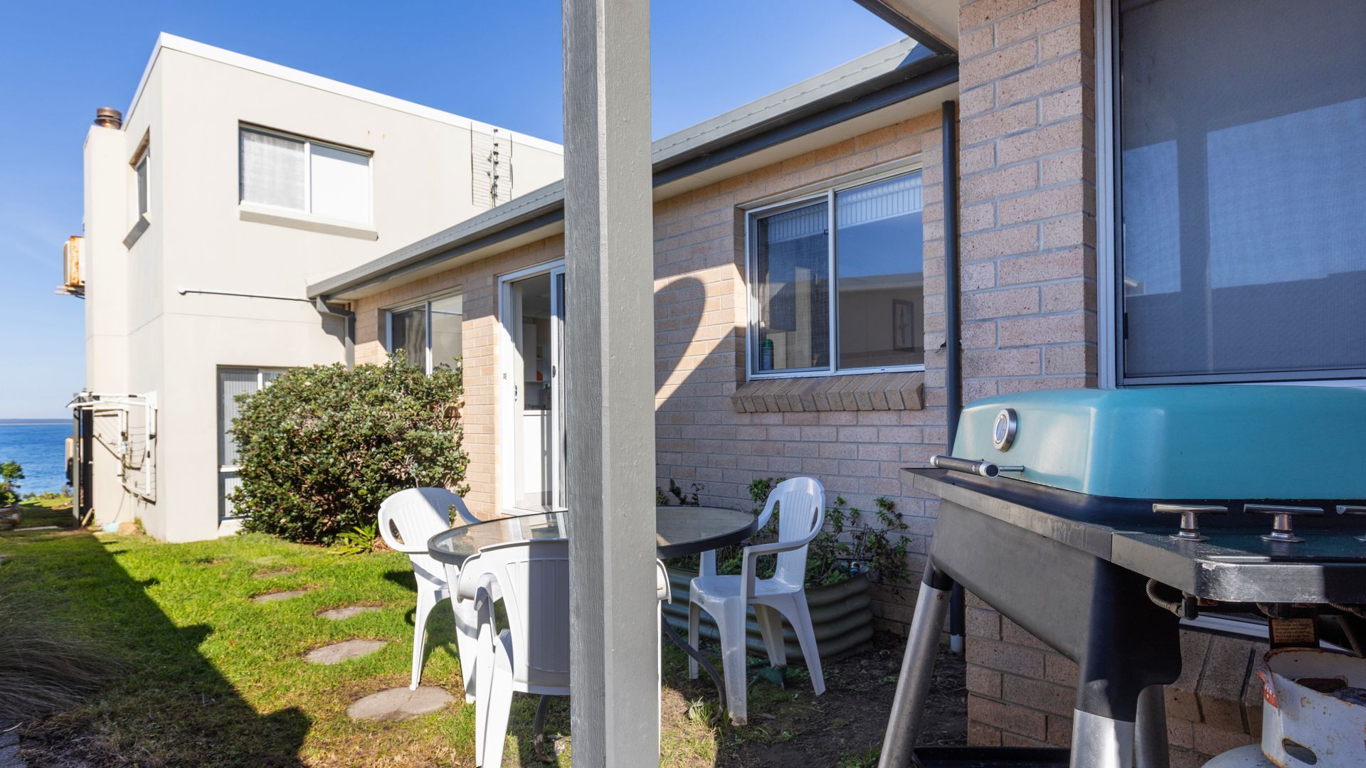 Une maison moderne dotée d’un patio, d’un barbecue et offrant une vue sur l’océan.