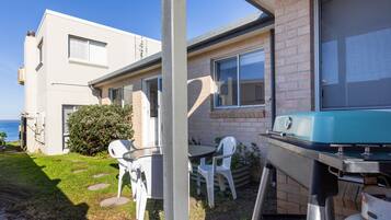 Une maison moderne dotée d’un patio, d’un barbecue et offrant une vue sur l’océan.