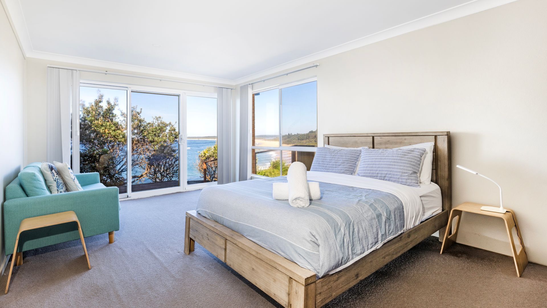 Un dormitorio con una cama grande, vista al mar y un balcón.