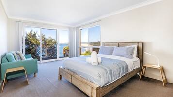 Un dormitorio con una cama grande, vista al mar y un balcón.