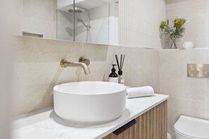 Une salle de bain avec un lavabo blanc, un miroir et des toilettes.