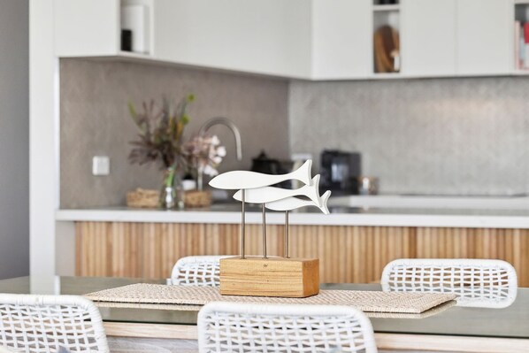 Une cuisine moderne avec un plan de travail blanc, un meuble en bois et un coin repas comprenant une table et des chaises.