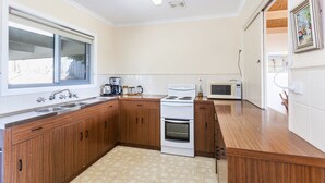 A kitchen with wooden cabinets, a stove, a microwave, and a window.