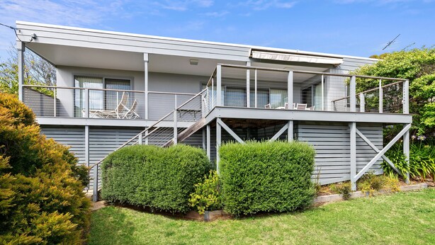 A two-story house with a balcony, a staircase, and a well-maintained garden.