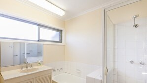 A bathroom with a bathtub, a shower, a sink, and a window above the mirror.