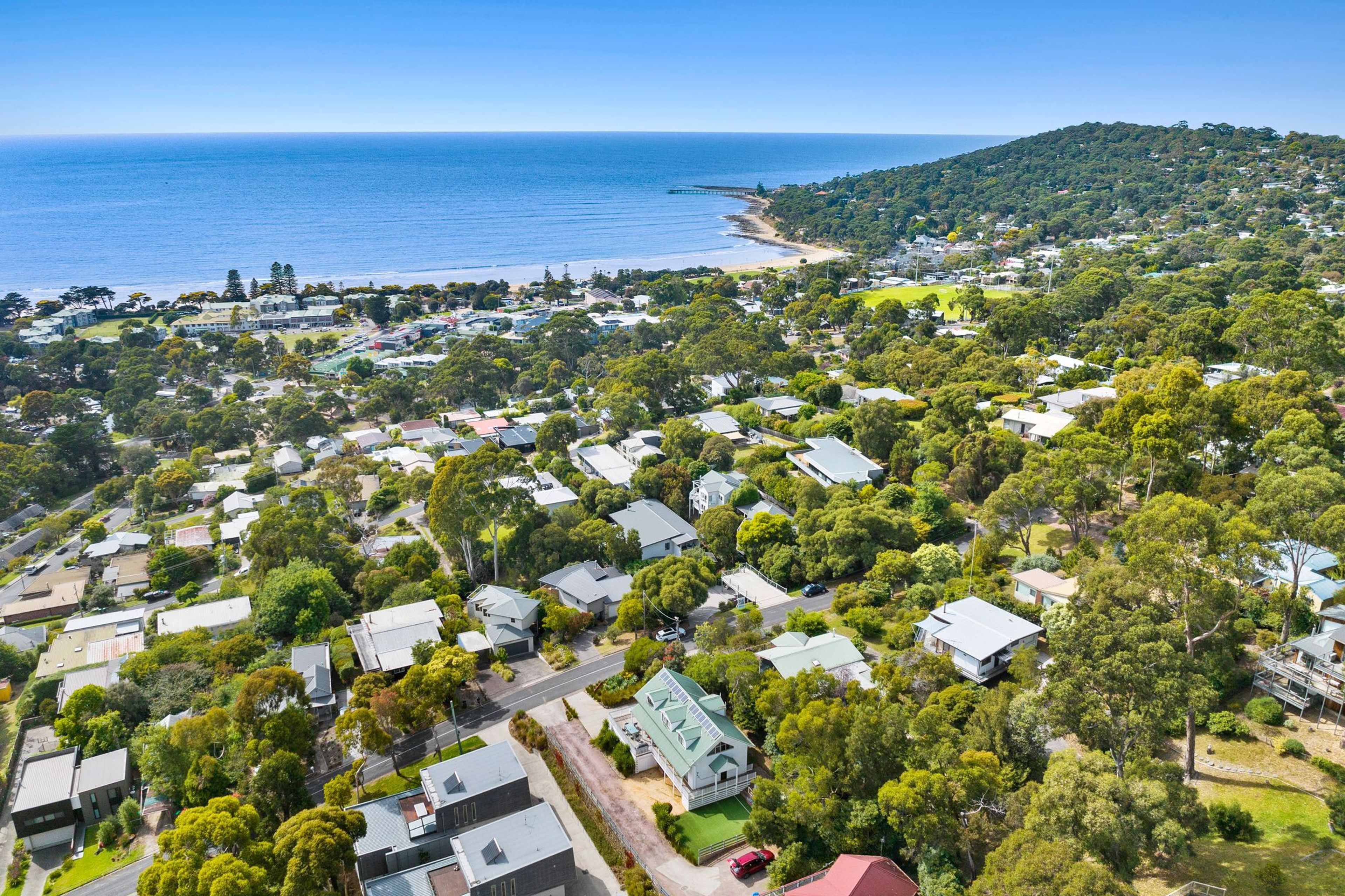 A residential area with houses, a beach, and a hilly landscape.