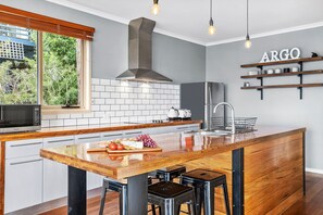 A modern kitchen with a wooden island, a built-in microwave, and a stainless steel refrigerator.