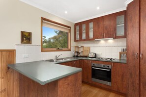 A modern kitchen with wooden cabinets, a built-in oven, and a large window.