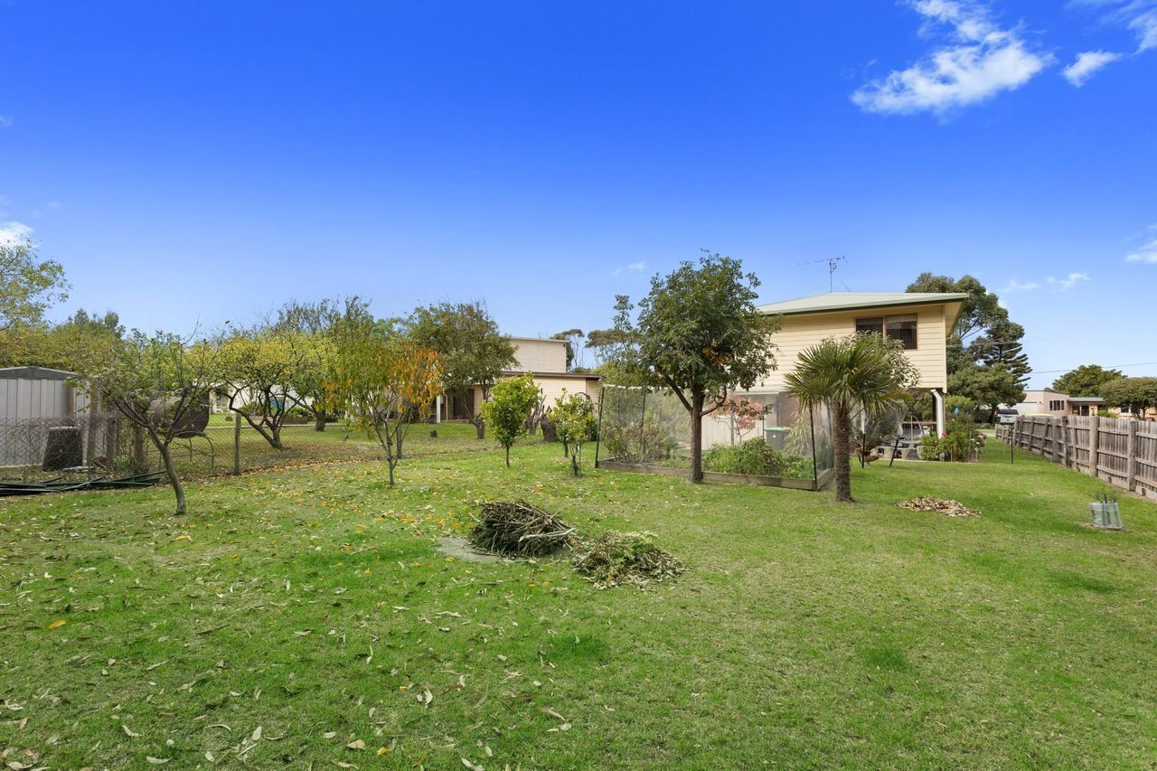 A residential property with a well-maintained lawn, a variety of trees, and a two-story house with a visible satellite dish.
