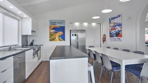 Una cocina moderna con armarios blancos, electrodomésticos de acero inoxidable, una isla grande con taburetes de bar y dos carteles en las paredes.