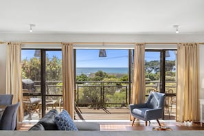 Un salon spacieux doté d’une grande porte-fenêtre coulissante donnant sur un balcon avec vue sur la mer.