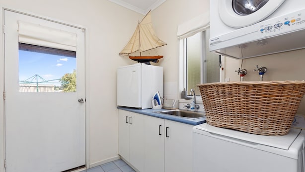 A compact kitchen with a washing machine, a sink, and a window with a view of a bridge.