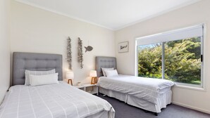 A bedroom with two beds, a large window, and a view of trees.