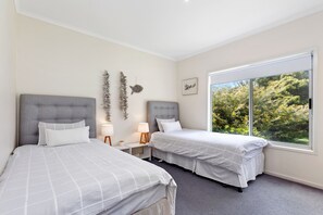 A bedroom with two beds, a large window, and a view of trees.