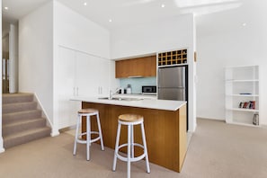 A modern kitchen with a central island, stainless steel appliances, and wooden accents. - Apollo Blue 11 (Apollo Bay)