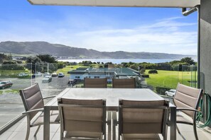 A balcony with a table and chairs overlooking a golf course and a body of water. - Apollo Blue 11 (Apollo Bay)