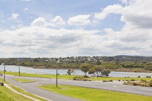 A road curving around a body of water with a residential area in the background. - Four Kings 3 (Anglesea)