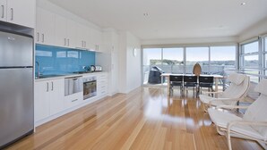 A modern kitchen with white cabinets, a stainless steel refrigerator, and a blue countertop. - Four Kings 3 (Anglesea)