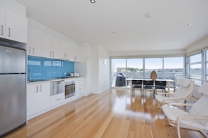 A modern kitchen with white cabinets, a stainless steel refrigerator, and a blue countertop. - Four Kings 3 (Anglesea)