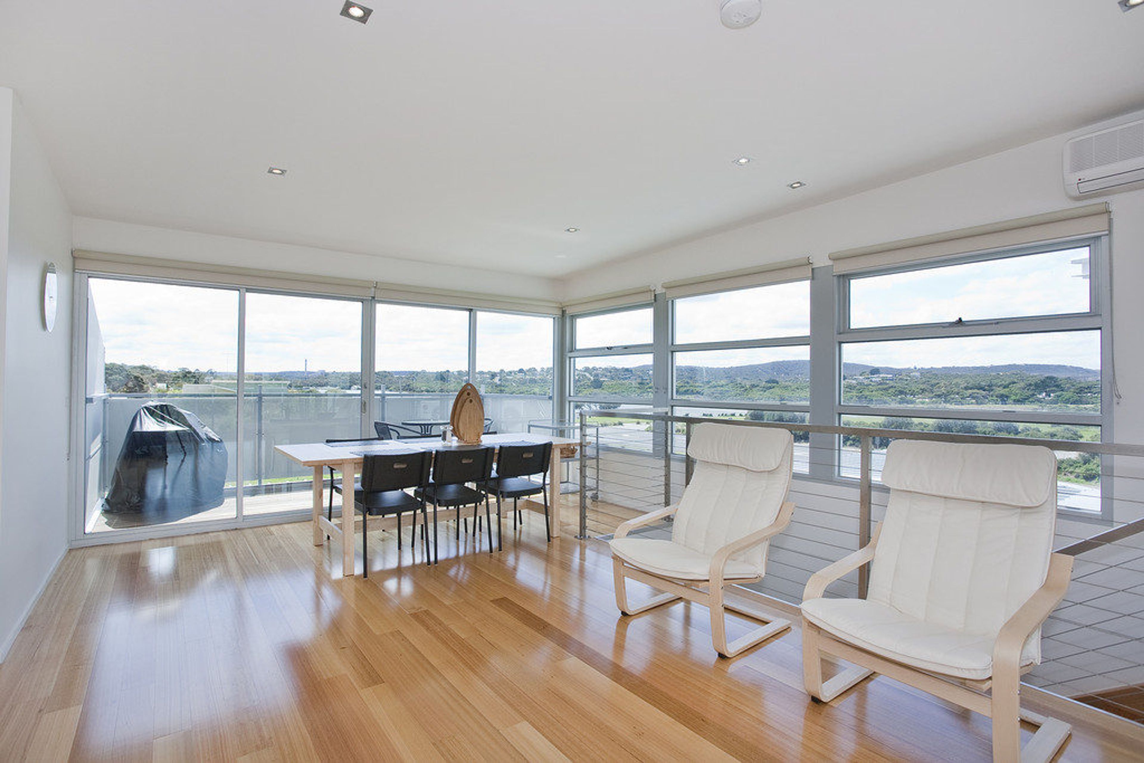 A spacious room with large windows, a dining table with chairs, and a view of the cityscape.