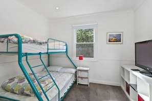 A bunk bed room with a television and a window.