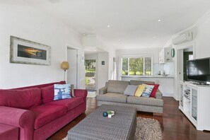 A living room with a red sofa, a grey sofa, and a television on a cabinet.