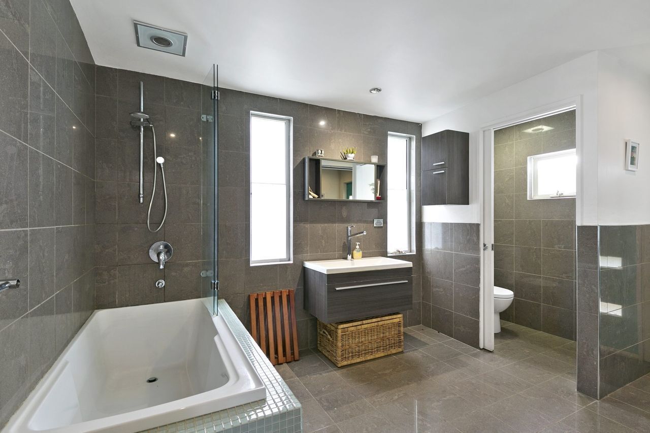 A modern bathroom with a bathtub, a shower, a sink, and a toilet.